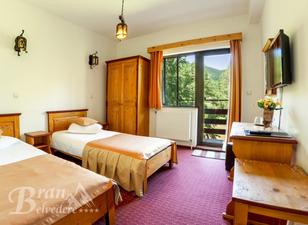 Cameră cu două paturi separate, mobilier din lemn și balcon