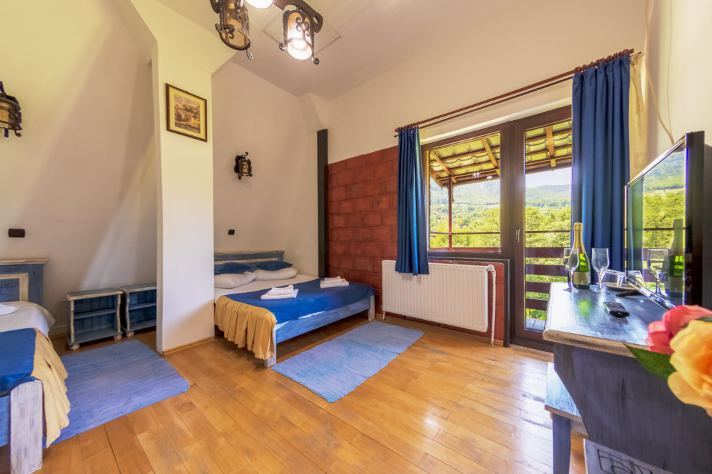 Cameră cu mobilier albastru și balcon cu vedere spre munte